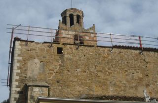 Una imatge de les baranes de protecció en la intervenció de la coberta de l'església de Cartellà i, al fons, el campanar, la setmana passada - Autor: FERRER, J.