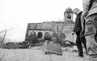 El párroco Alfonso Garciandía en el exterior de la iglesia junto a una piedra de la torre lanzada a más de 50 m - Autor: ONDIKOL